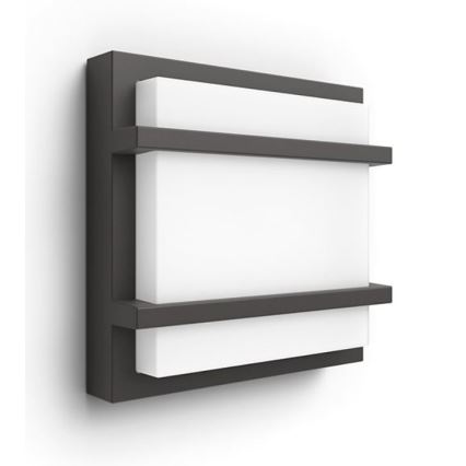 Nástené svietidlo s tmavosivým rámom a bielym svetlom sa nachádza na bielej stene. Svietidlo je štvorcového tvaru a má dve tmavosivé priečky.