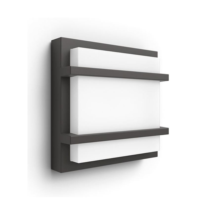 Nástené svietidlo s tmavosivým rámom a bielym svetlom sa nachádza na bielej stene. Svietidlo je štvorcového tvaru a má dve tmavosivé priečky.