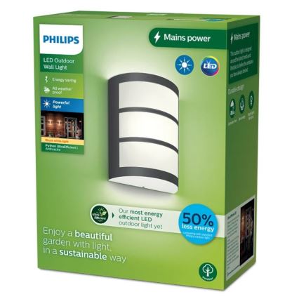 LED vonkajšie nástenné svietidlo Philips je zobrazené na obale. Svietidlo je sivé s tromi vodorovnými svetlými pruhmi. Balenie propaguje úsporu energie a odolný dizajn. Text na obale: „LED Outdoor Wall Light“, „Energy saving“, „All weather proof“, „Powerful light“, „Mains power“, „Our most energy efficient LED outdoor light yet“, „Enjoy a beautiful garden with light, in a sustainable way“, „50% less energy comparing with standard halogen light“.