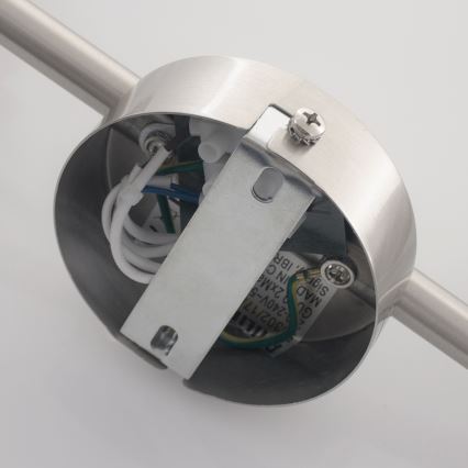 Kovová svietidlová objímka s pripojenými vodičmi je prichytená k kovovej tyči. Viditeľné sú aj technické údaje: 240V~50HZ, GU10, MAD, SIG, IN C, ZXMA5,IBR.