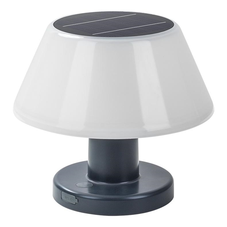 Solárna lampa s bielym tienidlom v tvare zrezaného kužeľa, na vrchu s integrovaným solárnym panelom, stojí na tmavosivej podstavci s USB portom. Lampa je umiestnená na bielom pozadí.