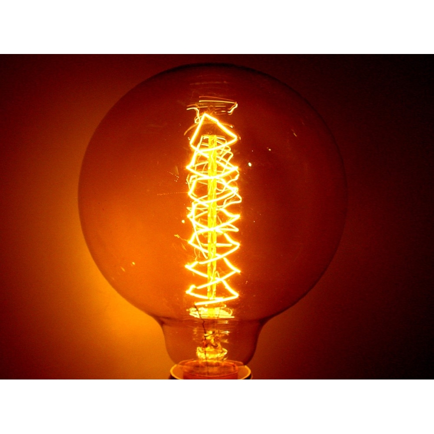Žiarovka svieti. Jej vlákno má tvar špirály. Svetlo žiarovky je intenzívne oranžové.