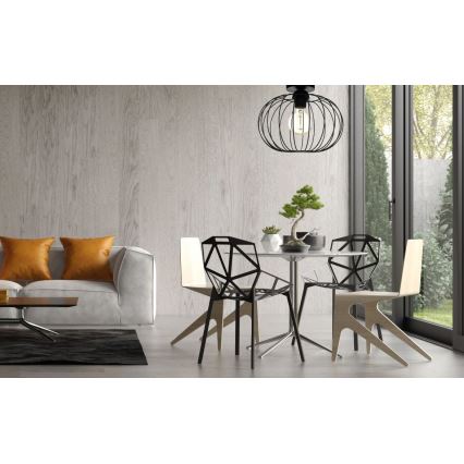 Svietidlo visí nad jedálenským stolom so štyrmi stoličkami v modernom interiéri. Dve stoličky sú čierne, dve svetlé drevené. Na stole je bonsaj.