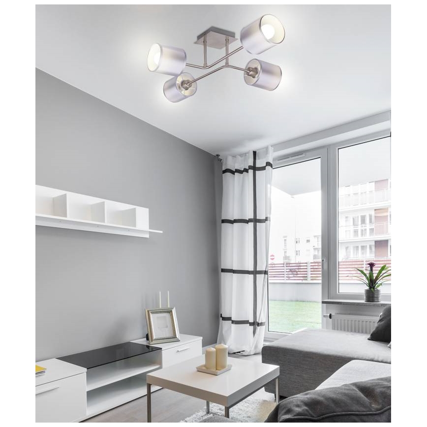 Stropné svietidlo s piatimi cylindrickými tienidlami svieti v obývacej izbe. Svietidlo je pripevnené k stropu a je súčasťou modernej izby s nábytkom v neutrálnych farbách.