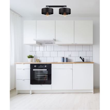 Dvojité stropné svietidlo s čiernymi tienidlami a viditeľnými žiarovkami sa nachádza v kuchyni s bielymi skrinkami a drevenou pracovnou doskou.