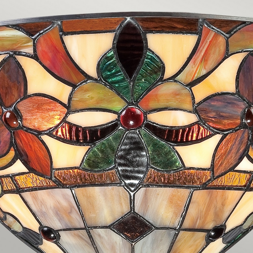 Tieniaca časť lampy zobrazuje kvetinový vzor v hnedých, zelených a červených odtieňoch vitráže. Je to miskovitý tvar s geometrickým spodkom.