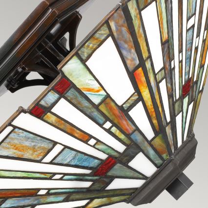 Tielňová lampa s farebnými sklenenými panelmi v tvare vejára je pripevnená k tmavej kovovej základni. Panely sú usporiadané do geometrického vzoru v odtieňoch modrej, zelenej, oranžovej, červenej a bielej.