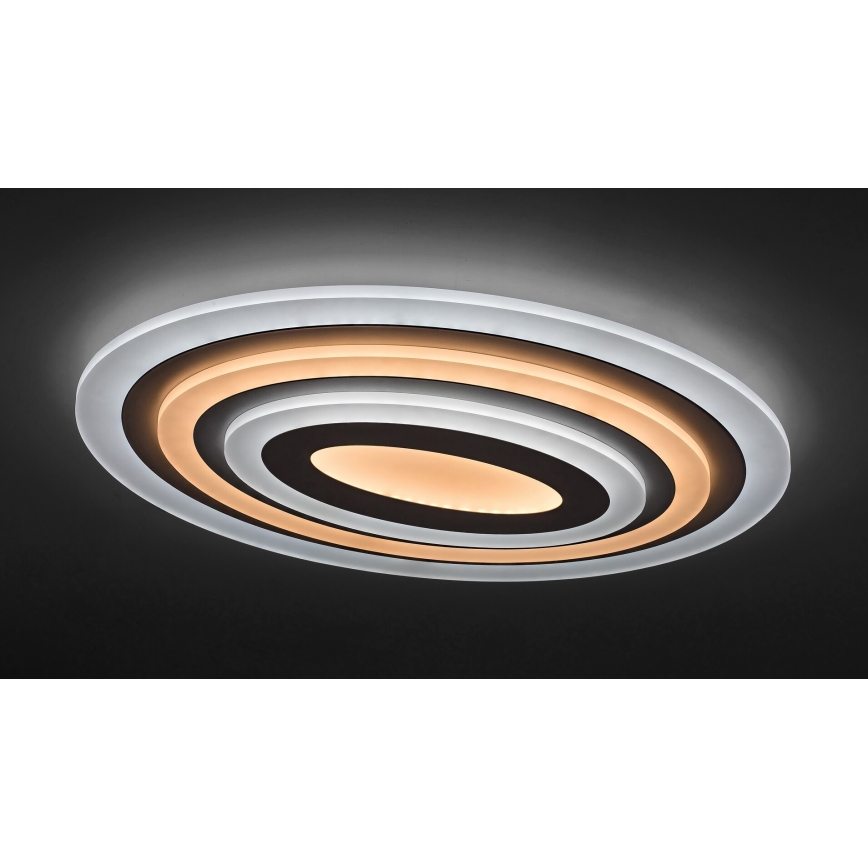 Svietidlo svieti na tmavom strope. Oválne svietidlo má viacero koncentrických kruhov, vnútorný je svetložltý. Vonkajší kruh je priesvitný.