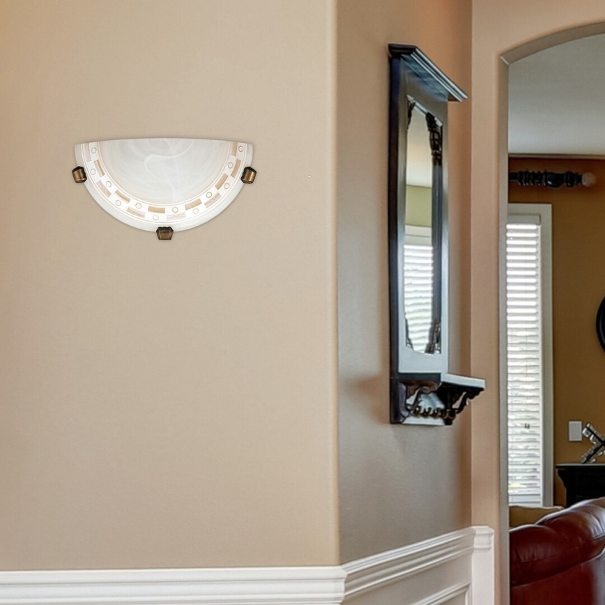 Polkruhový nástenný svietidlo s mliečnym sklom a hnedými kovovými prvkami je pripevnené na svetlohnedej stene. Svietidlo je umiestnené v chodbe s bielymi lištami a vedľa tmavého zrkadla s poličkou.