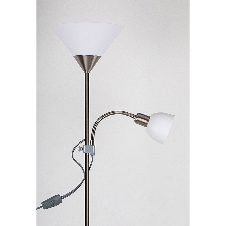 Stojacia lampa s dvoma tienidlami, pričom jedno je pripevnené na ohybnom rameni. Lampa je strieborno-šedá, tienidlá sú biele. Jednoduché pozadie.