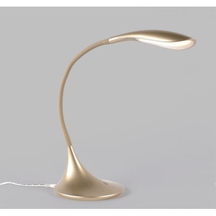 Stolná lampa s oblým zlatým ramenom a podstavcom svieti. Je umiestnená na jednotvárnom svetlosivom pozadí.