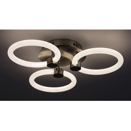 Svietidlo s tromi kruhovými LED svetlami svieti. Stred svietidla je tmavokovový, kruhy sú biele a pripevnené na kovové držiaky. Svietidlo je pripevnené k stropu.