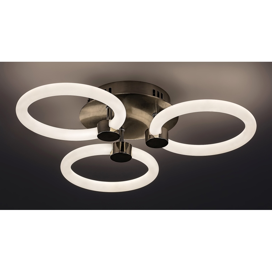 Svietidlo s tromi kruhovými LED svetlami svieti. Stred svietidla je tmavokovový, kruhy sú biele a pripevnené na kovové držiaky. Svietidlo je pripevnené k stropu.