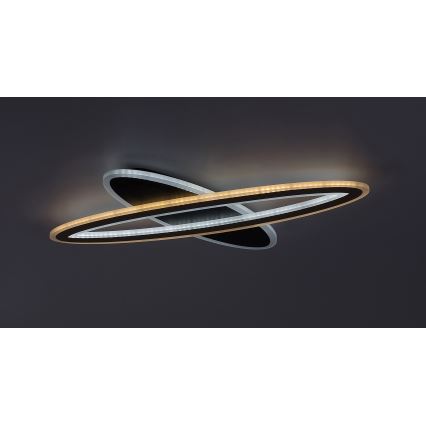 Svietidlo s dvoma prekrývajúcimi sa oválnymi LED prstencami, vnútorný zlatý, vonkajší biely, je pripevnené k stropu. Svietidlo je čiernej farby.