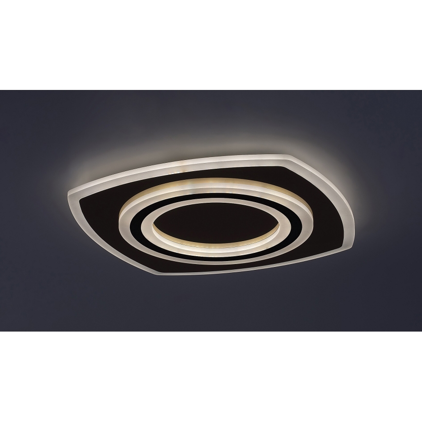 Svietidlo svieti na tmavomodrom strope. Má štvorcový tvar s oblými rohmi a obsahuje sústredné kruhy: tmavý vnútorný kruh, obklopený dvoma svetlými kruhmi.