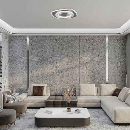 Svetlo s dvojitým kruhovým rámom je osadené na strope. Svietidlo osvetľuje modernú obývaciu izbu s rohovou sedačkou a nízkym konferenčným stolíkom. Stenu tvorí sivý materiál s výraznou štruktúrou.