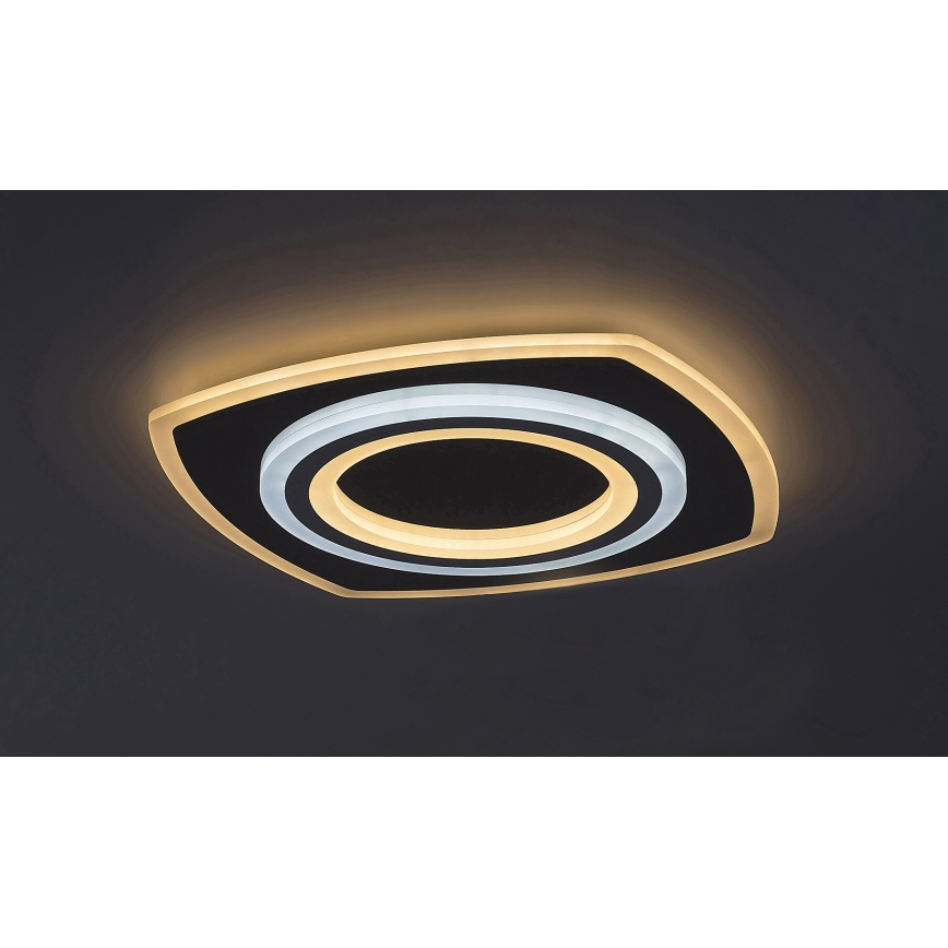 Svietidlo svieti na tmavom strope. Má štvorcový tvar s vnútorným kruhovým dizajnom a dvojitým okrajom, ktorý svieti teplým bielym a studeným bielym svetlom.