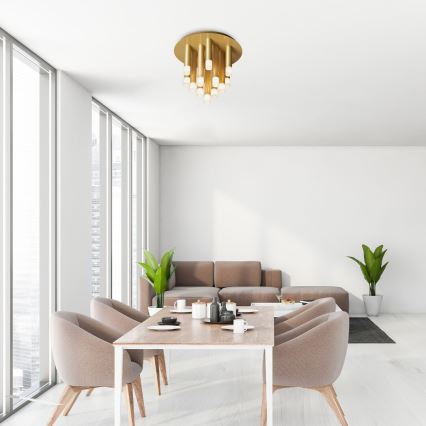 Stropné svietidlo s viacerými svetlami visí v svetlej jedálni. Jedálenský stôl s hnedými stoličkami a hnedá sedačka sú v miestnosti s veľkými oknami.