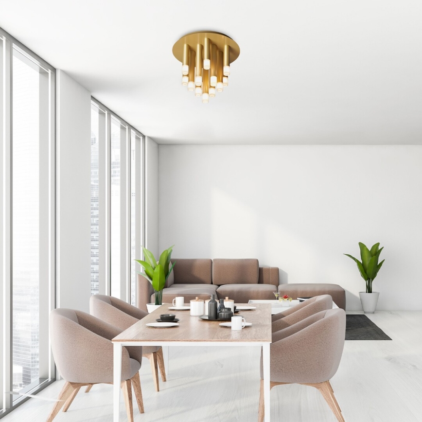 Stropné svietidlo s viacerými svetlami visí v svetlej jedálni. Jedálenský stôl s hnedými stoličkami a hnedá sedačka sú v miestnosti s veľkými oknami.