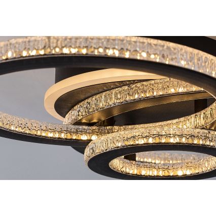 Svietidlo svieti. Je tvorené niekoľkými prekrývajúcimi sa čiernymi kruhmi, osadenými kryštálikmi, ktoré obklopujú svetelný zdroj. Konštrukcia je moderná.