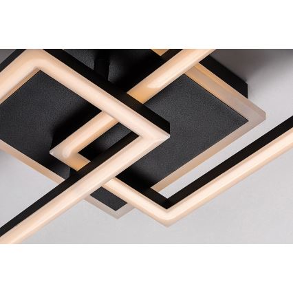 Svietidlo s prepletenými čiernymi rámami a teplými LED svetlami je pripevnené k stropu. Svetlá sú umiestnené vo vnútri rámov, ktoré vytvárajú geometrický vzor.