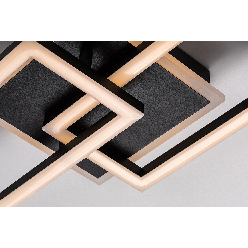 Svietidlo s prepletenými čiernymi rámami a teplými LED svetlami je pripevnené k stropu. Svetlá sú umiestnené vo vnútri rámov, ktoré vytvárajú geometrický vzor.