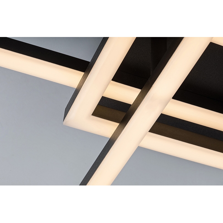 Svietidlo svieti. Jeho čierny rám obsahuje svetelné LED diódy, ktoré vytvárajú teplé svetlo. Svietidlo je pripevnené k stropu.