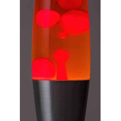 Lávová lampa s oranžovou tekutinou a pohybujúcimi sa červenými bublinami. Spodná časť lampy je tmavosivá, kovová. Svetlo presvitá cez oranžovú tekutinu.