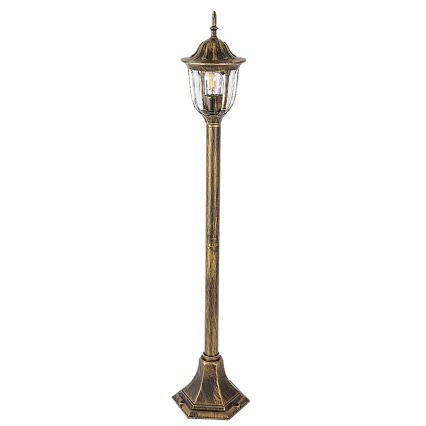 Záhradná lampa stojí na kamennej dlažbe. Okolité prostredie tvorí kvitnúci ker hortenzií a záhradný nábytok, vrátane dvoch oranžových kresiel.