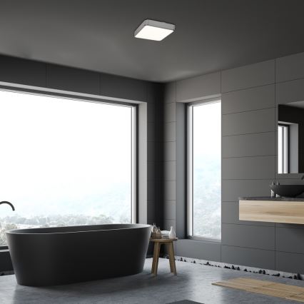 Čierna voľne stojaca vaňa sa nachádza v tmavosivej kúpeľni s veľkými oknami s výhľadom na krajinu. Nad vaňou je stropné svetlo.