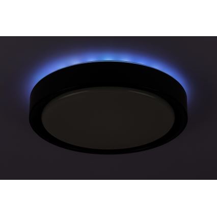 Okrúhle stropné svietidlo svieti. Jeho okraj je osvetlený modrým svetlom. Svietidlo je namontované na strope.