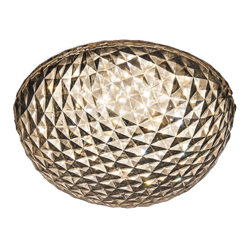 Svietidlo svieti. Jeho tienidlo je guľového tvaru a má fasetovaný povrch z priehľadného materiálu. Svietidlo je umiestnené na bielom pozadí.