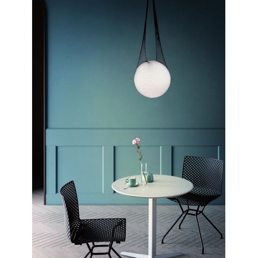Guľová lampa visí zo stropu na čiernych šnúrkach. Je umiestnená nad bielym okrúhlym stolom s dvoma čiernymi stoličkami v jedálni s tyrkysovými stenami.