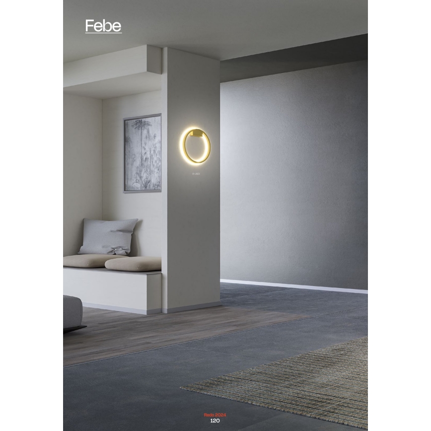 Kruhová nástenná lampa svieti v interiéri. Lampa je umiestnená na svetlej stene, v blízkosti sedacej súpravy a tmavosivej podlahy. Text v spodnej časti: Reao 5004 120.