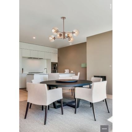 Lustr so šiestimi sklenenými guľami visí nad okrúhlym jedálenským stolom s bielymi stoličkami v jedálni. V pozadí je kuchyňa. V pravom dolnom rohu je nápis INDOOR.