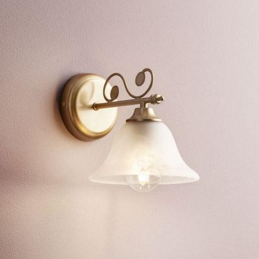 Nástenná lampa so zvončekovitým tienidlom z mliečneho skla je pripevnená na stenu. Lampa je zlatohnedej farby s ozdobným ramenom. Svetlo je viditeľné cez tienidlo.