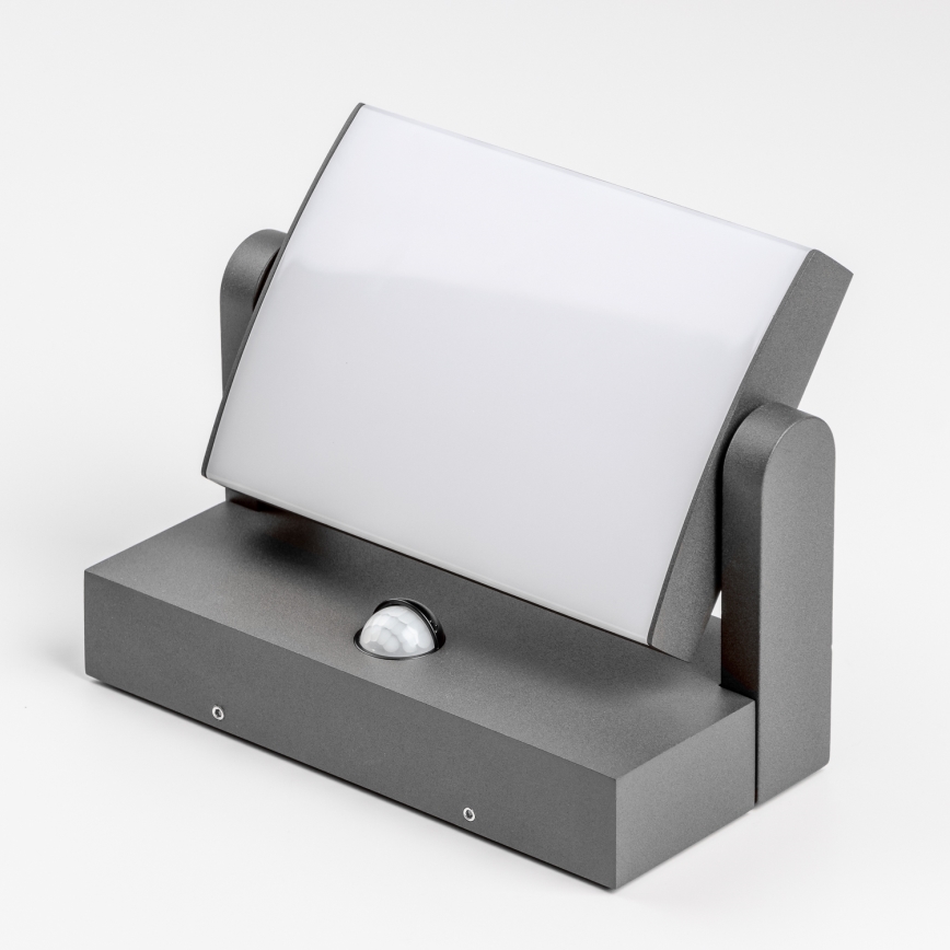 Svietidlo s pohybovým senzorom svieti. Je šedé, má plochý dizajn a nastaviteľný uhol svetla. Nachádza sa na bielom pozadí.