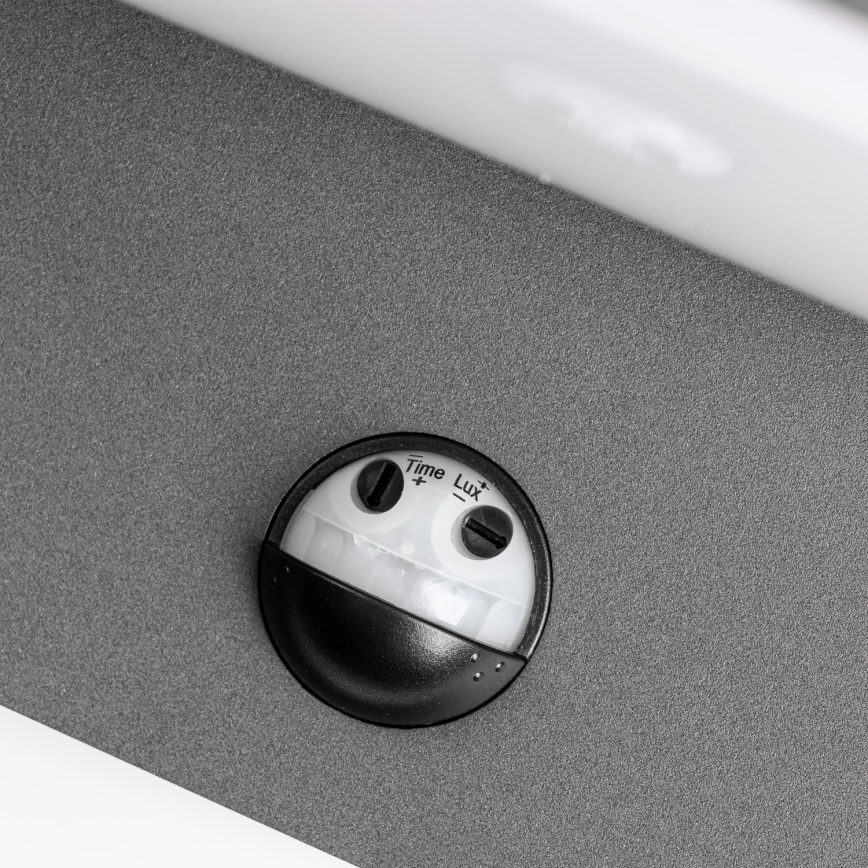 Senzor pohybu s nastavením času a luxov je umiestnený na sivej ploche. Na senzore sú viditeľné ovládacie prvky s označením „Time +“ a „Lux -“.