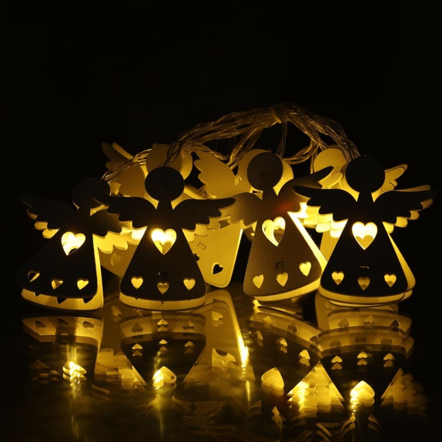 Drevené anjely s LED svetlami svietia. Anjely sú zavesené na šnúrke a sú usporiadané v skupine. Odrážajú sa na tmavom povrchu.