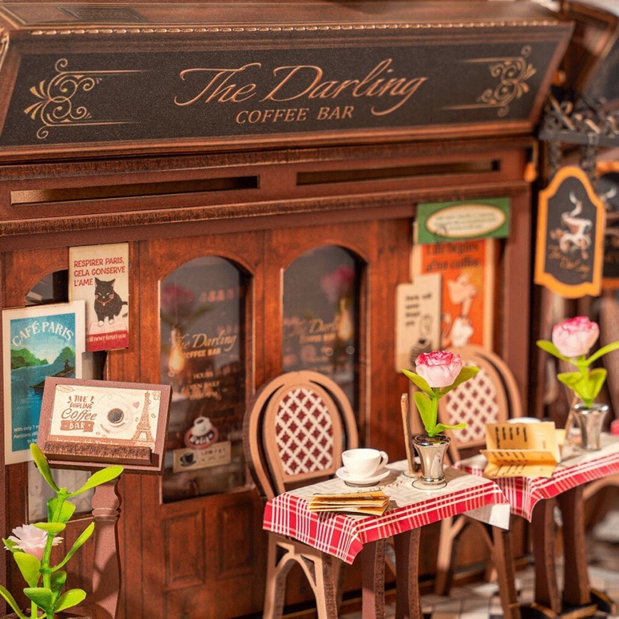 Miniatúrna kaviarňu „The Darling Coffee Bar“ s dvomi stolíkmi a stoličkami, na ktorých sú šálky a jedálne lístky. Na stenách sú plagáty s textom: „CAFE PARIS“, „RESPIRER PARIS, CELA CONSERVE L'AME“. Na jednom stojane je nápis: „A DIE A CUP OF COFFEE BAR“.