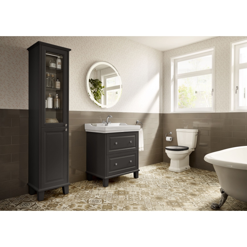 Tmavosivá kúpeľňová skrinka s policami stojí v kúpeľni s dlaždicami a sanitárnou keramikou. Kúpeľňa obsahuje umývadlo, toaletu, vaňu a okrúhle zrkadlo.