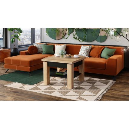 Nízky konferenčný stolík s výsuvnou časťou stojí pred oranžovou sedačkou v obývacej izbe. Na stolíku sú šálky a váza s kvetmi. Stolík sa nachádza na koberci s geometrickým vzorom.