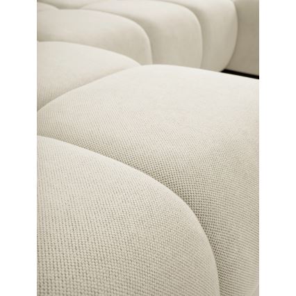 Svetlo béžová sedačka s guľatými modulmi je detailne zobrazená. Textúra poťahu je hrubá, tkaná. Sedačka je časťou väčšieho nábytku.