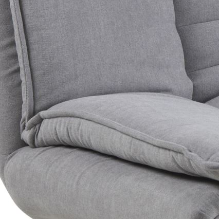 Šedá pohovka s mäkkými vankúšmi je čiastočne zobrazená. Vankúše sú opierkami na sedenie. Pohovka sa zdá byť čalúnená látkou s jemnou textúrou.