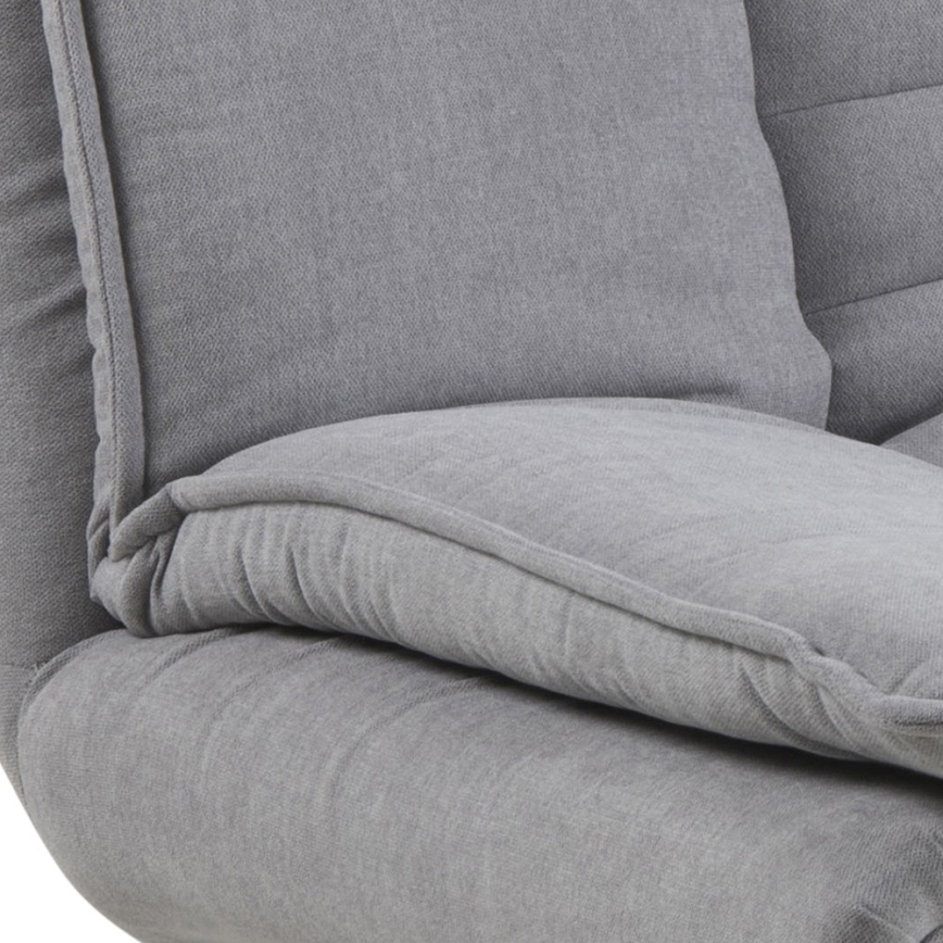 Šedá pohovka s mäkkými vankúšmi je čiastočne zobrazená. Vankúše sú opierkami na sedenie. Pohovka sa zdá byť čalúnená látkou s jemnou textúrou.