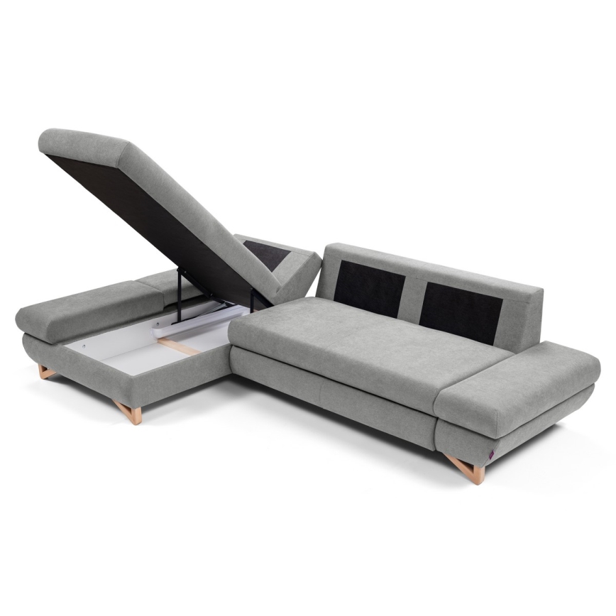 Rohová sedačka s otvoreným úložným priestorom v sivej látke s drevenými nožičkami. Sedačka je rozkladacia. Je umiestnená na bielom pozadí.