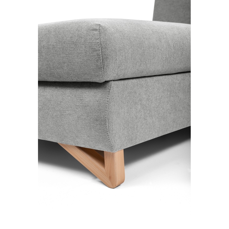 Sivá sedačka s drevenými nohami v tvare písmena V stojí na bielom pozadí. Sedačka je čalúnená sivou textíliou.