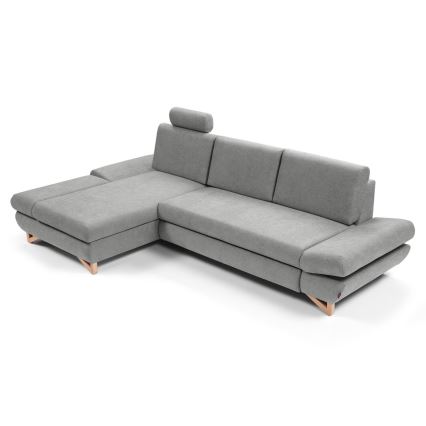 Rohová sedačka s opierkou hlavy odpočíva na svetlom pozadí. Sedačka je sivá, má drevené nohy a rozkladací element.