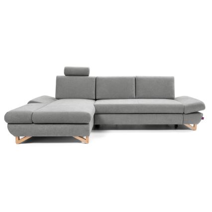 Rohová sedačka sivého čalúnenia stojí na svetlom drevenom podstavci. Sedačka je v tvare písmena L a má opierku hlavy. Je umiestnená na bielom pozadí.