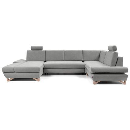 Rohová sedačka stojí na bielom pozadí. Sedačka je sivá, má drevené nohy a opierky hlavy. Je rozsiahla a tvarom pripomína písmeno U.